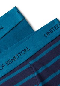 Dvě složené dvojice modro pruhovaných pánských boxerek s širokým tyrkysovým pasem, na kterém je nápis "UNITED COLORS OF BENETTON".