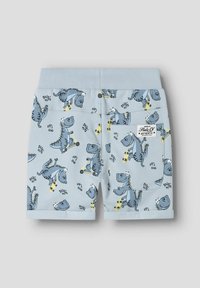 Blå bomullsshorts med dinosaurtryck i olika mönster, elastisk midja, rullade ärmslut och en bakficka med en etikett.