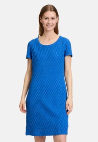 Kurzes, knielanges Kleid aus strukturiertem blauen Stoff mit rundem Ausschnitt. Das Kleid hat eine lockere Passform und dezente Muster.