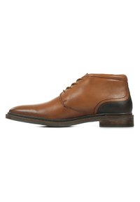 Stivaletto in pelle marrone con punta arrotondata, design con lacci, tacco nero a contrasto e dettagli cuciti lungo la suola.