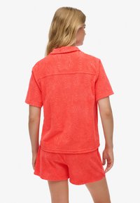 Koralowa teksturowana koszula z krótkim rękawem i kołnierzykiem, zygzakowaty wzór, zestawiona z pasującymi szortami. Luźny krój.