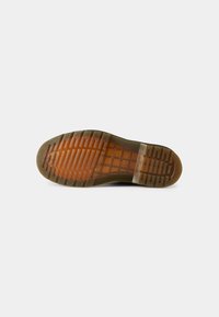 Semelle en caoutchouc marron avec une finition texturée et imprimée ; accents transparents orange ; présente des rainures distinctes pour la traction et l'adhérence.