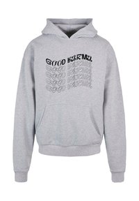 Haut à capuche gris avec une poche avant, des manches longues et une capuche. Le texte "GOOD KARMA" est imprimé en noir avec un design ondulé.