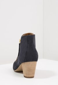 Granatowe botki za kostkę wykonane z zamszu, z teksturowanym drewnianym obcasem oraz bocznym zamkiem błyskawicznym z złotymi akcentami.