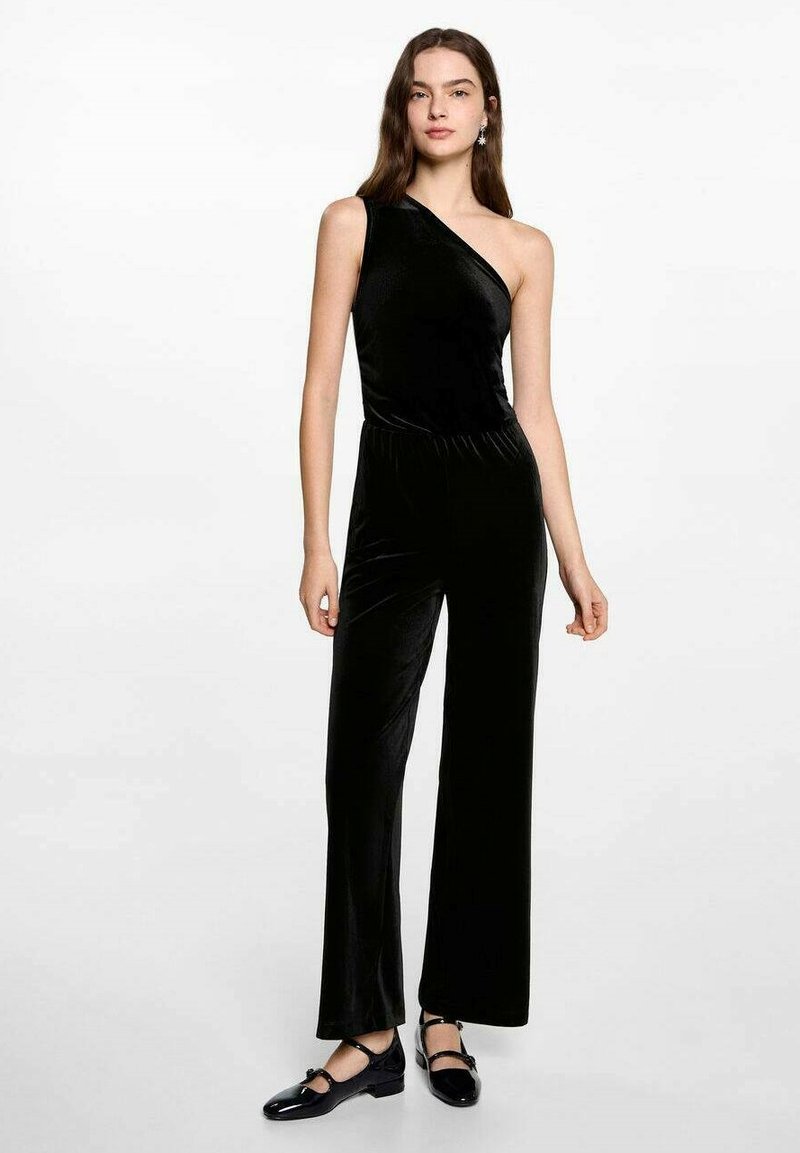 Black velvet jumpsuit with a single shoulder strap, wide legs, and elastic waistband. Finished with shiny black shoes. Simple, elegant design.