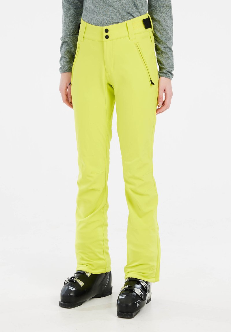 Neon gele skibroek met een slim fit, twee met rits afgesloten zakken, een verstelbare tailleband en op maat gemaakte pijpen voor een slank ontwerp. Zwarte skibotten worden gedragen.