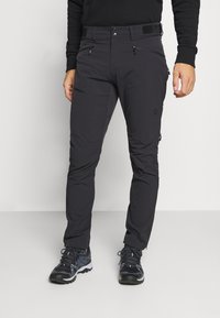 Čierne vonkajšie nohavice so slim fit strihom, vybavené zipsovými vreckami, bezpečným pásom a ľahkým, elastickým materiálom pre pohyblivosť.