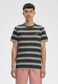 T-shirt a righe in nero e crema, a maniche corte, collo tondo. Presenta un piccolo logo ricamato sul lato sinistro del petto.