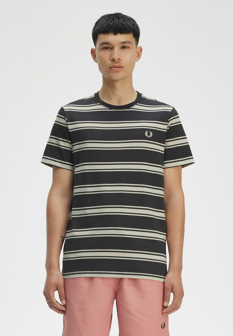 T-shirt a righe in nero e crema, a maniche corte, collo tondo. Presenta un piccolo logo ricamato sul lato sinistro del petto.