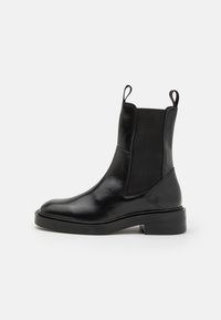 Black leather ankle boot with elastic side panels, round toe, and pull tabs; flat sole with a moderate heel. Smooth texture and sleek design.