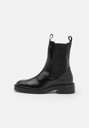 Schwarze Leder-Ankle-Boots mit elastischen Seitenpaneelen, runder Zehenpartie und Schlaufe zum Anziehen; flache Sohle mit moderatem Absatz. Glatte Textur und elegantes Design.