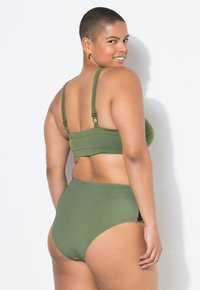 Olivově zelený bikinový set s krátkým topem a nastavitelnými ramínky a vysokým pasem. Hladký povrch, minimální kovové části a bezešvý design.