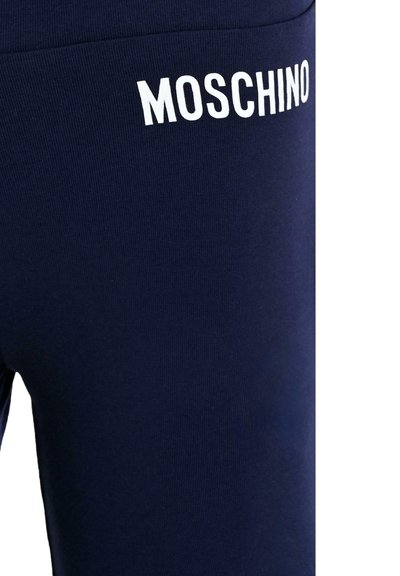 Granatowe legginsy wykonane z gładkiego materiału, z białym logo "MOSCHINO" na pasku. Projekt jest dopasowany do sylwetki i ma czyste wykończenie.