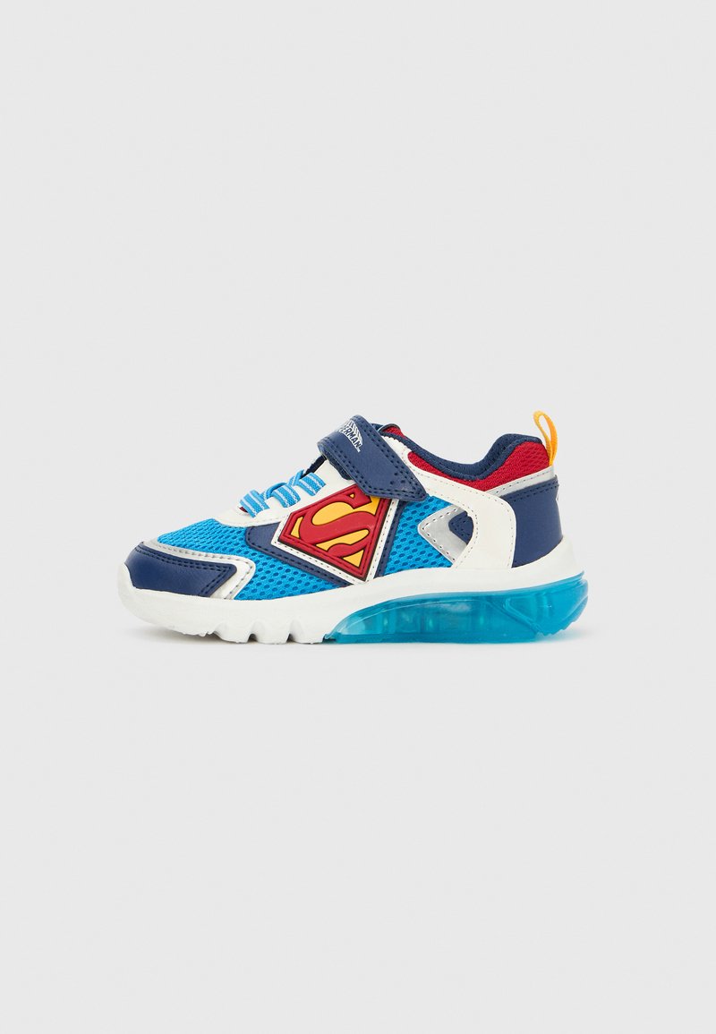 Sininen, valkoinen ja punainen lasten lenkkari Superman-logolla, tarrakiinnityksellä, valaisevalla läpikuultavalla pohjalla ja keltaisella kantalenkillä.