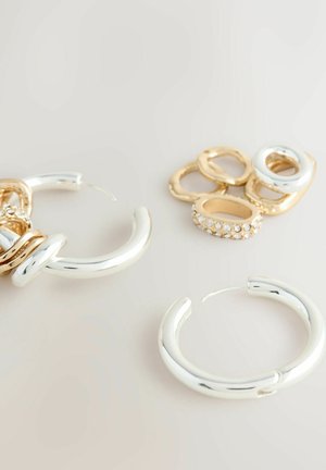 Silver hoop earrings with a smooth, reflective surface alongside gold and silver rings, including one with clear rhinestones.