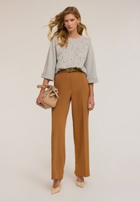 Pull gris avec embellissements, pantalon taille haute marron, et sac à main beige. Présente des jambes larges et un design élégant. Palette de couleurs neutres.