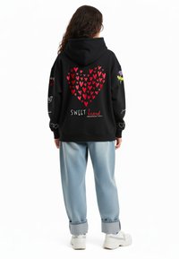 Felpa nera con cappuccio caratterizzata da un grande design a forma di cuore rosso, con la scritta "SWEET heart" e accenti floreali colorati sulle maniche. Vestibilità casual con cappuccio.