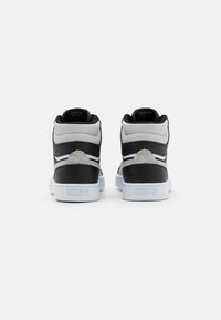 Black and gray high-top sneakers with white soles and golden accents. Features padded collar, textured panels, and logo on heel tab.