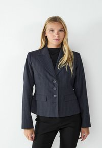 Navy pinstripe blazer with a fitted design, single-breasted front, three buttons, notched lapels, and two front pockets.