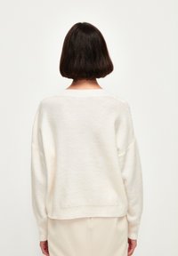 Maglione oversize color crema in un morbido e soffice knit. Presenta un collo e un orlo a coste con cuciture delle spalle dropped, che offrono una vestibilità rilassata.
