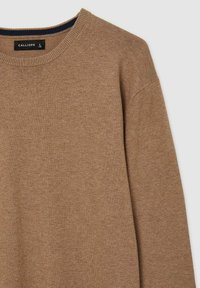Pull en tricot brun clair avec un col rond, des poignets côtelés et un col intérieur bleu foncé. Texture douce et coupe décontractée. Étiquette de la marque visible.
