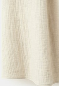 Tissu écru texturé avec des plis verticaux et horizontaux visibles et de légères ombres indiquant des plis.