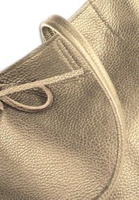 Leren tas in donkergrijs met een gestructureerd oppervlak, ronde vorm en decoratieve strikdetailing op de klep. Naadstiksels zijn zichtbaar.