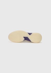 Talpa de sneaker cu un outsole din cauciuc bej texturat, având un design decorativ în violet și un model de profil în zigzag pentru aderență.