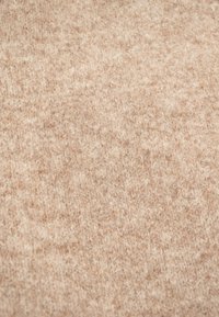 Tessuto di lana beige con una superficie morbida e testurizzata. Il materiale appare peloso con un motivo leggermente mélange in tutto.