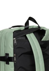 Zaino nero e verde menta con doppia cerniera, numerosi scomparti e una maniglia superiore per il trasporto. Tessuto strutturato con dettagli di cucitura.