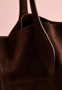 Brown suede tote bag with a smooth texture, featuring short handles and a simple, unembellished design.