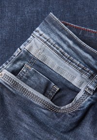 Jeans en denim bleu foncé avec une zone de poche légèrement décolorée, présentant des coutures contrastées et une poche plus petite sur le côté droit.