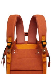 Le sac à dos synthétique orange présente des bretelles rembourrées, une couture robuste, des accents en métal et une poche zippée sur le côté. Les panneaux texturés améliorent la prise.