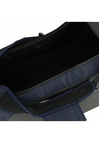 Borsa aperta blu navy e nera con spallaccio imbottito e tasca interna con zip visibile.