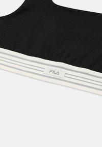 Svart ribbad sport-bh med ett vitt och blått randigt elastiskt band, med en Fila-logotyp sydd på bandet.