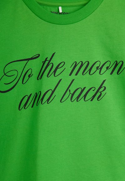 Πράσινο πουκάμισο από ύφασμα με τη φράση «To the moon and back» τυπωμένη με μαύρη καλλιγραφική γραμματοσειρά στο μπροστινό μέρος.