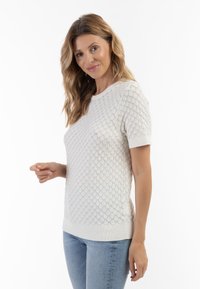 Hvid kortærmet sweater med struktureret, bølge-mønster. Ribbet halsudskæring og kant. Sammen med lyseblå jeans. Glat stoffinish.
