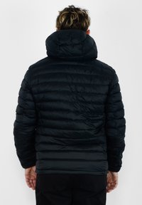Giubbotto a sacco nero con cappuccio, caratterizzato da sezioni trapuntate, texture liscia e polsini elasticizzati. Senza loghi visibili o dettagli aggiuntivi.