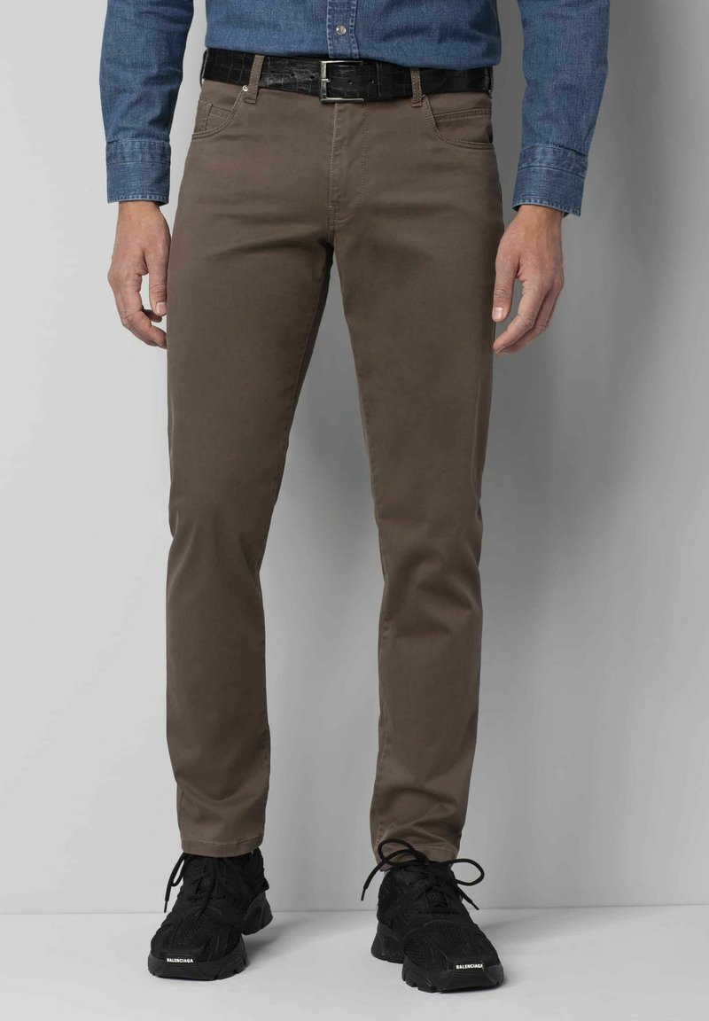 Pantalons slim fit marron en coton, dotés d'une texture lisse, d'un design à cinq poches, associés à des chaussures de sport noires et une ceinture noire texturée.