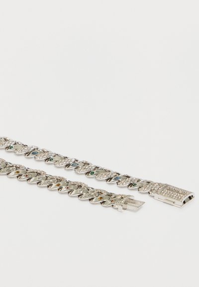 Duas pulseiras de corrente prateada com pedras preciosas coloridas embutidas e cristais transparentes, uma com fecho aberto, sobre um fundo branco.