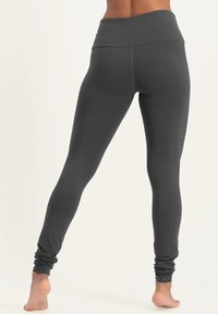 Graue Leggings mit hohem Bund, aus einem glatten, dehnbaren Stoff gefertigt. Die Beine haben an den Knöcheln geraffte Bündchen.