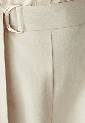 Beige fabric with a textured finish, featuring a wide waistband and a gold circular buckle accent. Clean, tailored lines and stitching details.