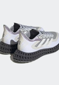 Zapatillas deportivas blancas y grises con parte superior de malla texturizada, tres franjas grises y un diseño de suela de rejilla negra. Presenta acentos reflectantes.
