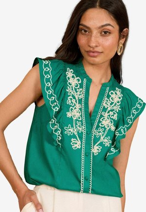 Blusa verde con maniche a volant, motivo floreale ricamato in crema, chiusura con bottoni frontale e tessuto leggero.