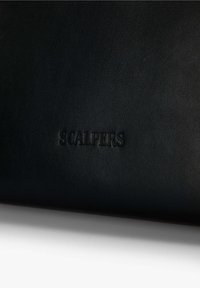 Cartera de cuero negra con una superficie texturizada, que presenta el logo en relieve "SCALPERS" en la parte inferior central. Diseño simple y rectangular.