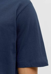 Camiseta de algodón azul marino con cuello redondo y mangas cortas; textura suave y costura ordenada visible en el dobladillo.