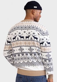 Maglione lavorato a maglia con base crema e motivi geometrici in blu navy, nero e beige. Polsini e orlo a coste, vestibilità confortevole, tema invernale.