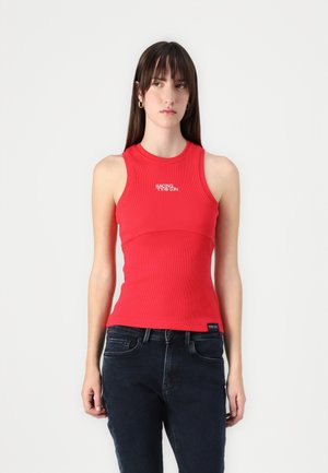 Top in cotone rosso a coste con un design aderente, scollatura rotonda e testo grafico "RACING" in bianco. Abbinato a jeans in denim scuro.