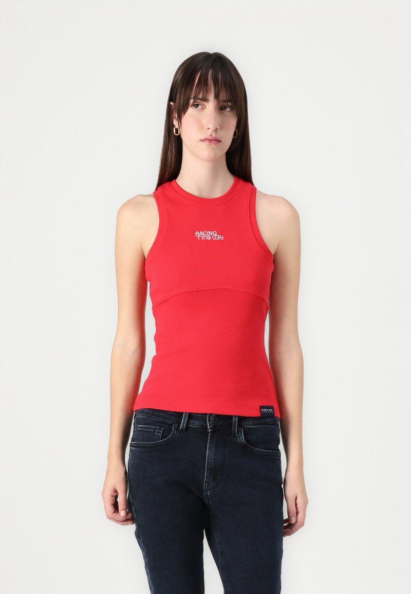 Top roșu cu dungi, cu un design mulat, decolteu rotund și text grafic "RACING" în alb. Asortat cu blugi negri din denim.