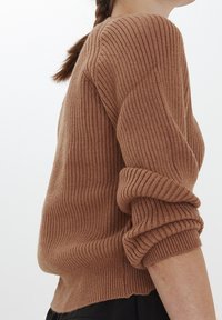 Maglione marrone a coste con scollatura rotonda e maniche arrotolate, caratterizzato da un lavoro a maglia testurizzato. Il design è morbido e informale.